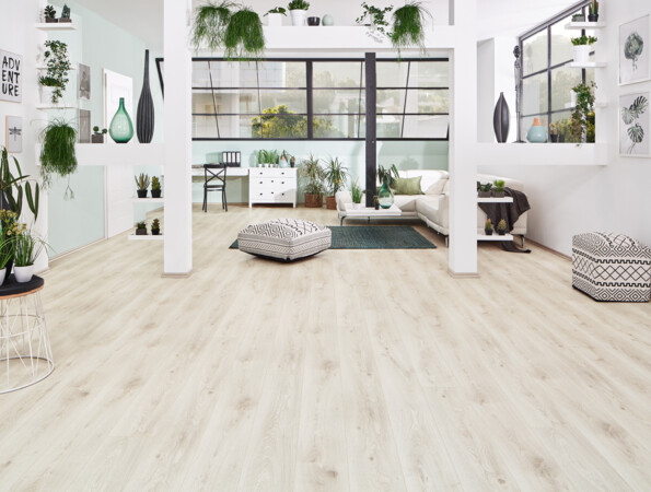 Bright living room with light laminate flooring from the series 'Vinto', greenery, and contemporary furniture.