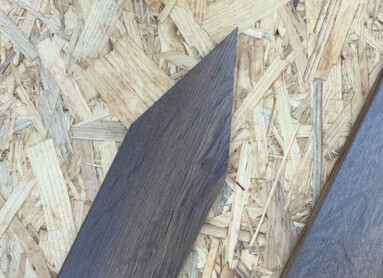 Dunkle Laminatdielen auf einer Spanplattenoberfläche.