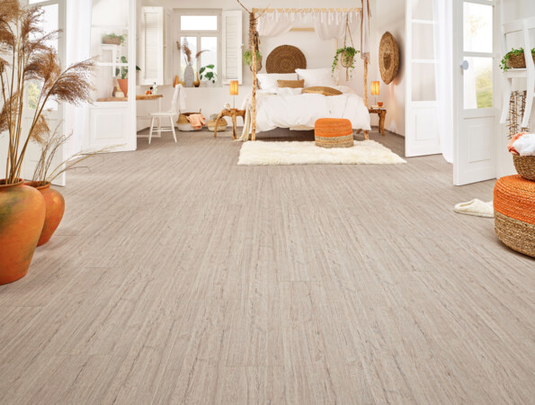 Helles Schlafzimmer mit Laminatboden der Serie 'Vinto', dekoriert mit Pflanzen, orangen Akzenten und einem gemütlichen Bett.
