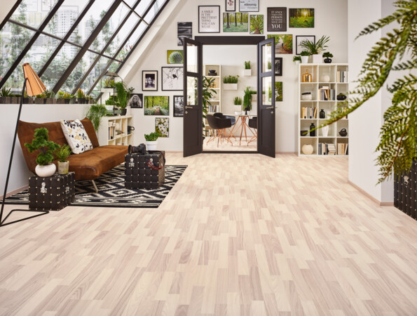 Modernes Wohnzimmer mit hellem Laminatboden der Serie 'Family', gemütlichem Sofa, Pflanzen und Wandbildern. Großer Fensterbereich sorgt für viel Tageslicht.