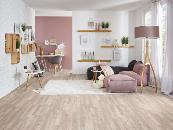 Living room with light laminate flooring, a cosy seating area, decorative shelves, and a work desk.