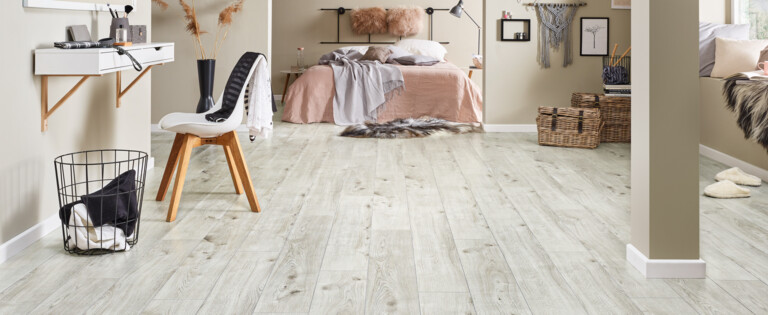 Moderner Raum mit hellem Laminatboden, gemütlicher Einrichtung und Dekoration. Schlafzimmer im Hintergrund mit Bett und Wanddekorationen.
