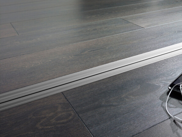 Smartphone with earphones on dark laminate flooring with a sleek design.