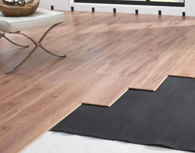 Laminate flooring installation in progress near a large window, showcasing partially laid planks and underlayment.