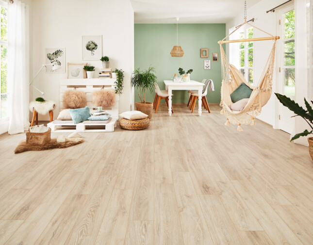 Bright living room with light laminate flooring from the series 'Vinto', cosy seating, and a hanging chair.
