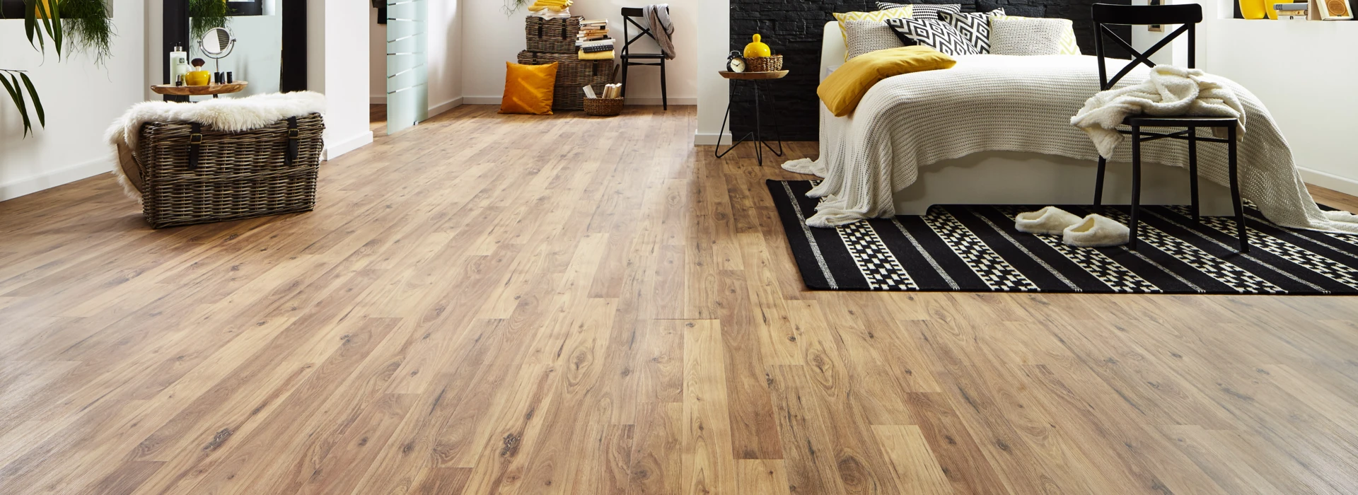 Modernes Schlafzimmer mit hellem Laminatboden, schwarzer Akzentwand, gemütlichem Bett und großen Fenstern für viel Tageslicht.