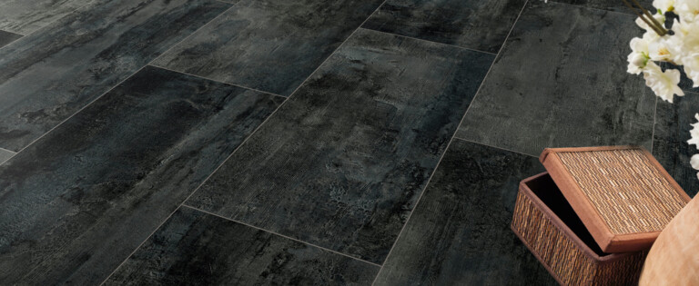 Dunkler Laminatboden der Serie 'Element flex' mit Blumenarrangement und offenem Korb auf der Seite, stilvoll und modern.