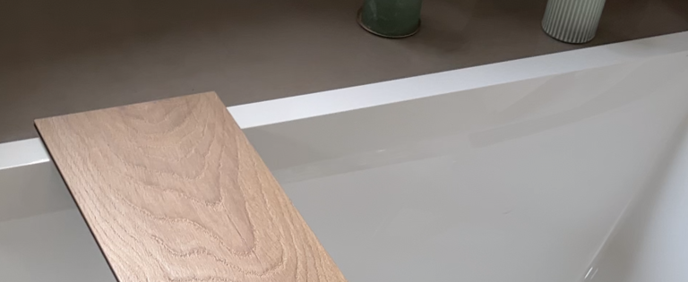 Holzoptik-Laminatbrett über Badewanne mit Kerzen im Hintergrund.