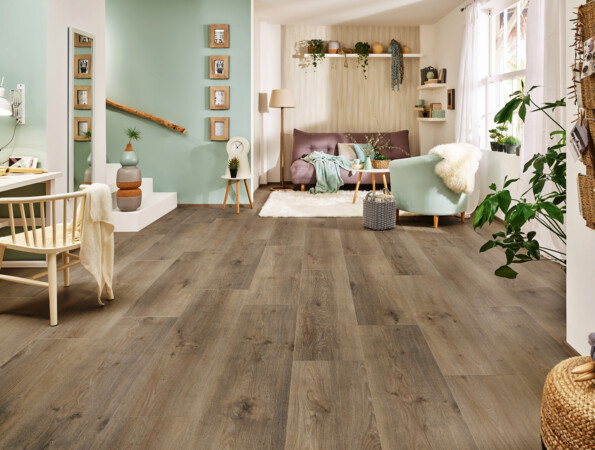 Helles Wohnzimmer mit Laminatboden der Serie 'Vinto', gemütlicher Sitzecke, Pflanzen und moderner Dekoration.