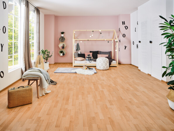 Helles Zimmer mit Laminatboden der Serie 'Family', einem Bett mit Rahmen, weichen Kissen und dekorativen Lichtern, großen Fenstern und Pflanzen.