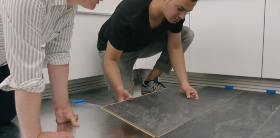 Zwei Personen verlegen Laminatboden in einer Küche.