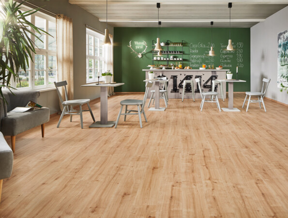 Gemütliches Café mit hellem Laminatboden der Serie 'Ambienta', modernen Möbeln und grüner Wand im Hintergrund.