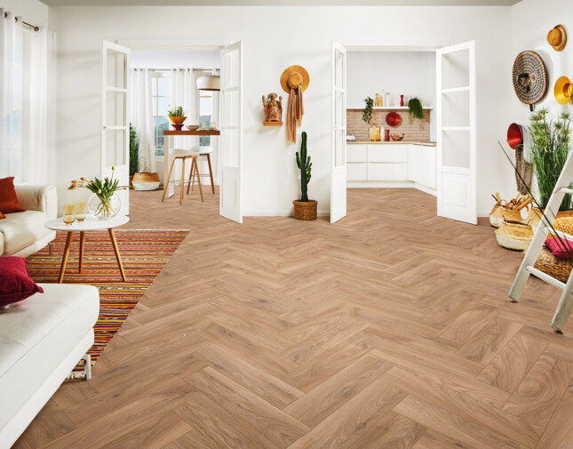 Heller Wohnraum mit Laminatboden, weißen Wänden und stilvollen Möbeln sowie Sicht in die Küche und den Essbereich. 