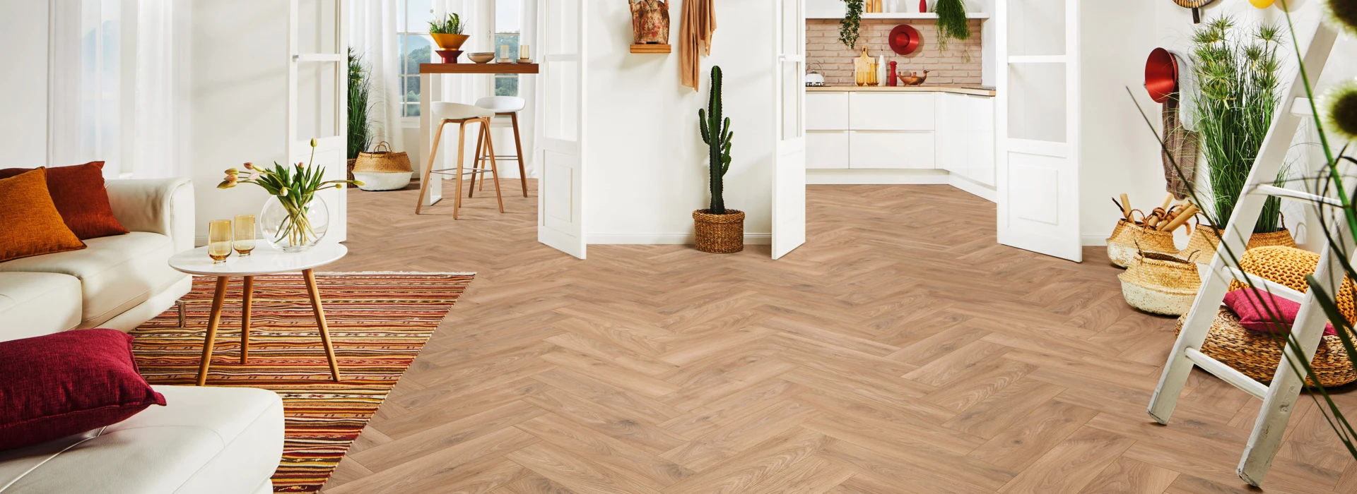Bright living space with herringbone laminate flooring, white furniture, and decorative plants.