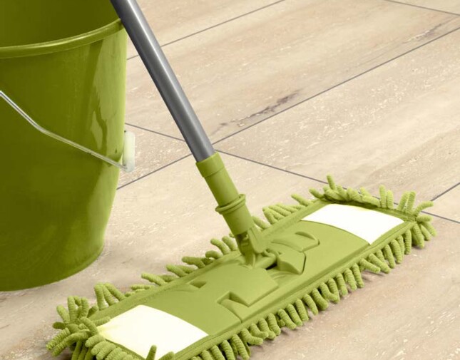Green mop and bucket on light laminate flooring.