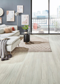 Heller Laminatboden in einem Wohnzimmer mit beiger Couch, grauen Wänden und Möbeln und einer hellen Fensterfront