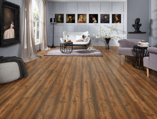 Ein stilvolles Wohnzimmer mit Laminatboden der Serie 'Vinto', grauen Sofas, Kunstwerken an der Wand und großen Fenstern, die natürliches Licht hereinlassen.