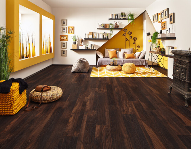 Wohnzimmer mit dunklem Laminatboden, gelben Akzenten, gemütlicher Sitzecke und dekorativen Regalen.