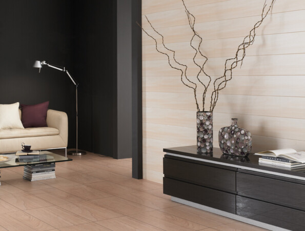 Living room with a cream sofa, glass coffee table, and black furniture with light wall coverings in the background.