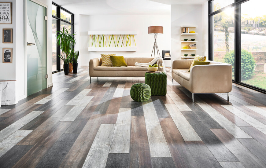 Bright living room with laminate flooring, beige sofas, and large windows overlooking a garden.