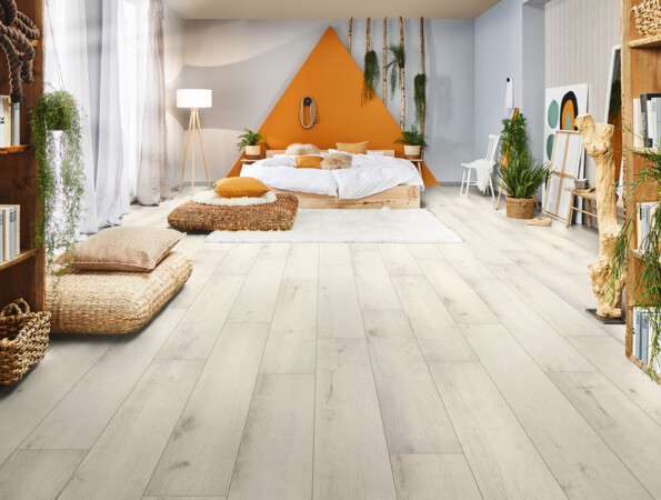 Schlafzimmer mit hellem Laminatboden, gemütlichem Bett und Pflanzen.