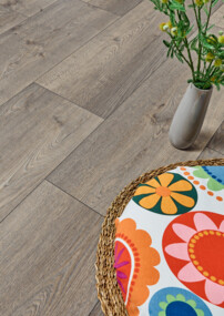 Laminatboden in Holzoptik mit bunter Sitzkissenauflage und Vase.