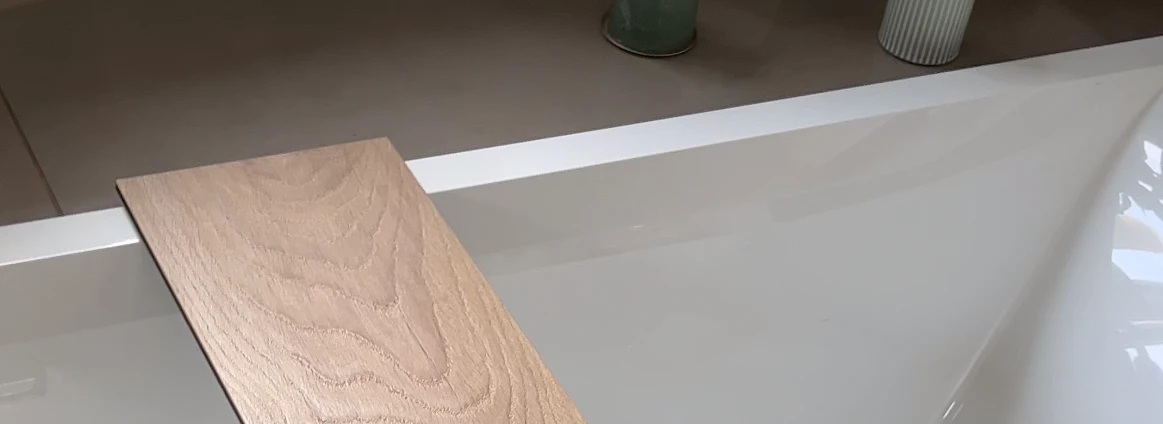Holzoptik-Laminatbrett über Badewanne mit Kerzen im Hintergrund.