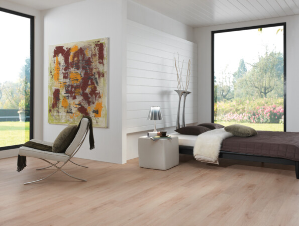 Schlafzimmer mit großen Fenstern, abstraktem Gemälde und hellem Laminatboden.
