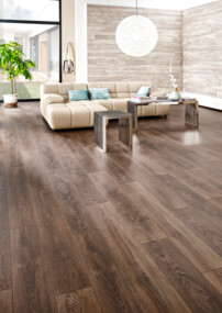 Helles Wohnzimmer mit dunklem Laminatboden, beigem Sofa, Barbereich und großen Fenstern.