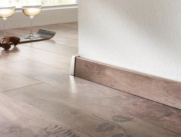 Moderne Laminatboden mit Holzoptik und eleganter Fußleiste entlang weißer Wand.