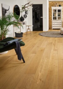 Modernes Wohnzimmer mit großen Fenstern, beigem Sofa und Pflanzen auf Laminatboden. Elegante, helle Einrichtung mit natürlichem Licht.