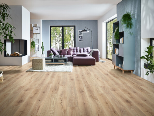 Modernes Wohnzimmer mit hellen Laminatboden, lila Sofa, Kamin, und großen Fenstern mit Blick ins Grüne. Pflanzen und Regale ergänzen das Ambiente.