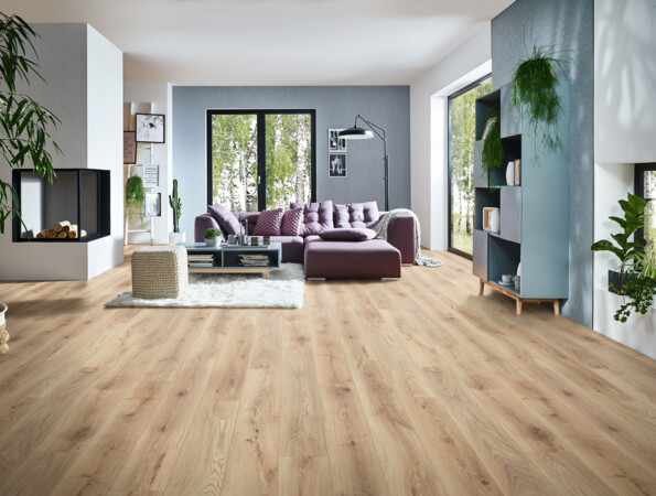 Modernes Wohnzimmer mit hellen Laminatboden, lila Sofa, Kamin, und großen Fenstern mit Blick ins Grüne. Pflanzen und Regale ergänzen das Ambiente.